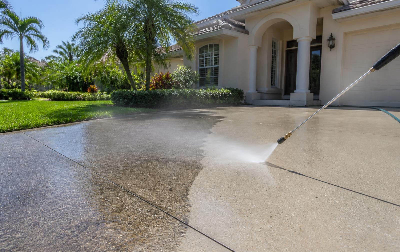 Pressure washer cleaning a concrete driveway in front of an Orlando home